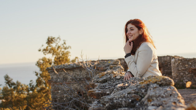 Beautiful girl with white dress explores an ancient Italian castle at sunset