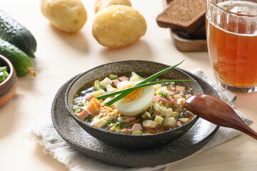 Russian summer okroshka soup with kvass. Freshness okroshka made of summer vegetables, cucumber, radish, potato, boiled eggs, onion. Close up.