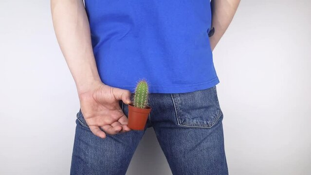 Concept. A man holds a cactus as a symbol of rectal pain. Varicose veins of the lower intestine. Pain in the rectum, hemorrhoids and pain in the excretory system of the body. Proctology