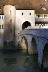 Close-up of chalk stone bridge over the river Doubs at little medieval town St-Ursanne, Canton...