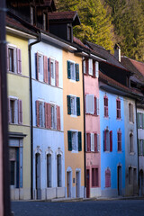 Naklejka premium Beautiful historic houses with colorful facades at the little medieval town of St-Ursanne, Canton Jura, on a winter morning. Photo taken February 7th, 2022, Saint-Ursanne, Switzerland.