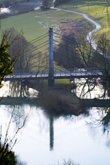 Aerial view of rope bridge near small medieval town Saint-Ursanne with river Doubs and defocus...