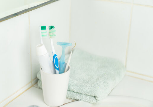 Toothbrush, toothpaste and face towel on basin in bathroom.