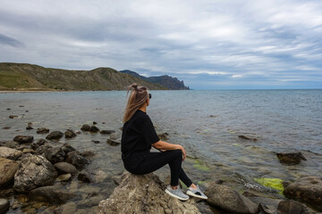Fototapeta na wymiar A girl on the shore of the Fox Bay - a bay of the Black Sea near the Kara-Dag mountain range. Crimea.