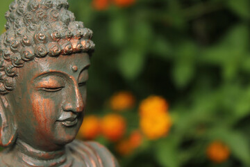 Buddha Statue in Garden with blurred flowers in background