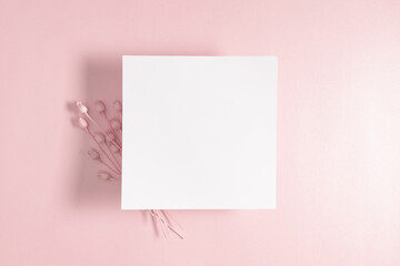 White paper empty blank, dry flowers, dried twig on pink background. Invitation card mockup on...