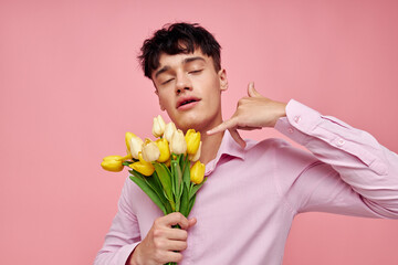 A young man in a pink shirt with a bouquet of flowers gesturing with his hands isolated background unaltered