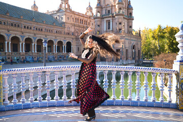 Obraz premium Young and beautiful typical Spanish woman dancing flamenco with urban and modern clothes, wearing her hair loose and long. Concept of flamenco cultural heritage of humanity.
