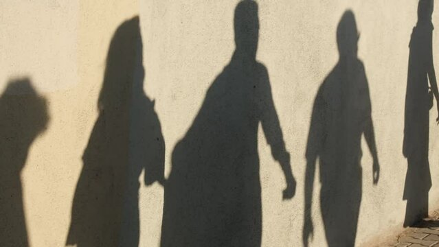 Shadows of walking crowd of people on a wall at street in slow motion