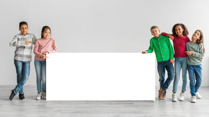 Fototapeta na wymiar Happy Diverse Kids Standing Near White Board Over Gray Background
