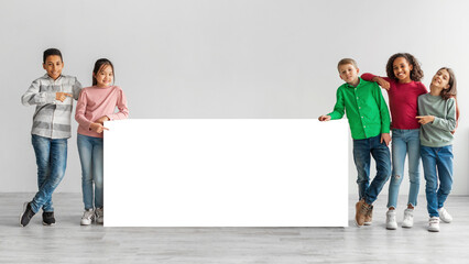 Happy Diverse Kids Standing Near White Board Over Gray Background