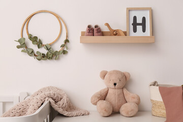 Wooden shelf with baby accessories and toys in child room. Interior design
