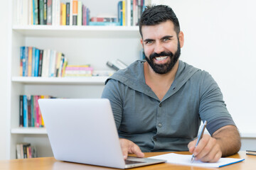 Laughing latin american teacher with hipster beard at computer