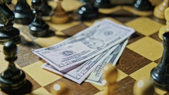 Money in US dollar bills on an old chessboard with retro chess pieces