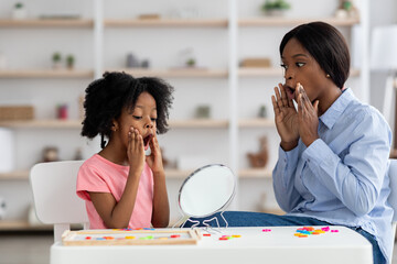 Female speech-language pathologist exercising with adorable little girl