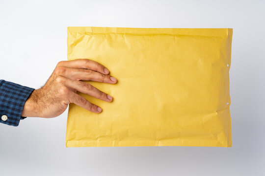 Male hand holding parcel post against white background