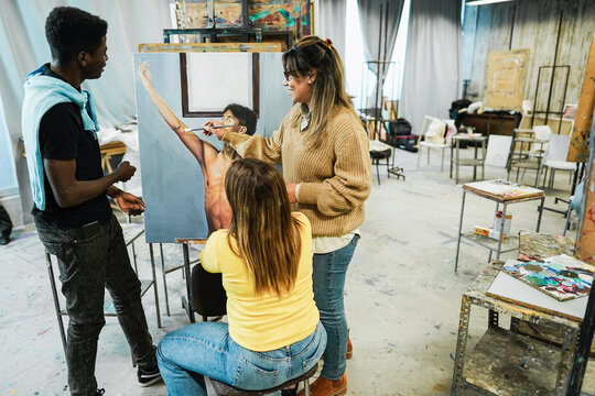 Mature teacher working with art students during painting class at school - Focus on woman face