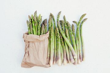 Organic green freshly cut asparagus stalks packed in eco-package on white background. Copy space, top view, horizontal image.  Asparagus officinalis. Spring healthy cooking idea concept