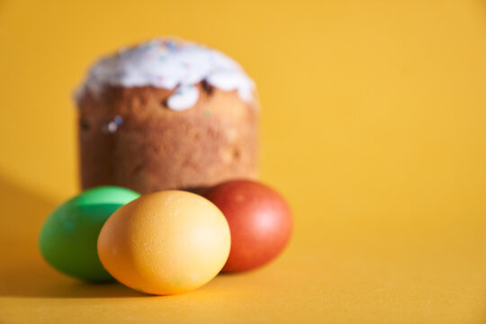 Colored Easter eggs on the background of an Easter cake. Yellow background with space to copy. High quality photo