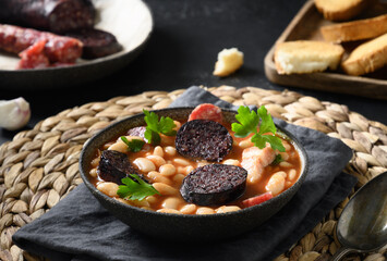 Fabada with chorizo, morcilla, sausage, haricot on black background. Spanish traditional warming...