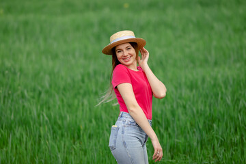Carefree happy woman in pink t-shirt and straw hat enjoying natu