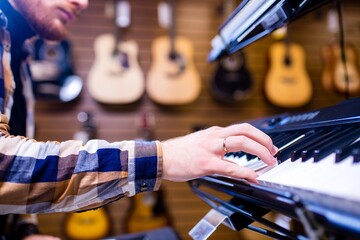 redhair ginger beard man is playing on piano in music store