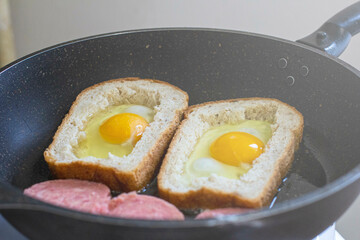 egg with sausage in bread, in a frying pan. cooking breakfast on a gas stove