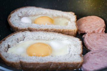 egg with sausage in bread, in a frying pan. cooking breakfast on a gas stove
