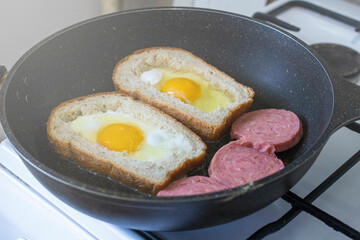 egg with sausage in bread, in a frying pan. cooking breakfast on a gas stove