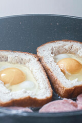 egg with sausage in bread, in a frying pan. cooking breakfast on a gas stove