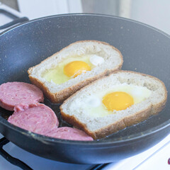 egg with sausage in bread, in a frying pan. cooking breakfast on a gas stove