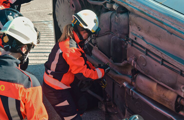 Fototapeta premium Female firefighter in front of a crashed car trying to rescue a victim