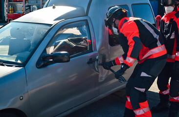 Firefighter opening the door of a crashed car with a pole