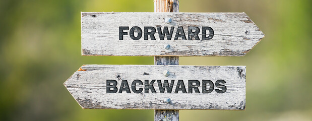 opposite signs on wooden signpost with the text quote forward backwards engraved. Web banner format.