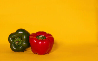red and green pepper on yellow background, on the left , front 