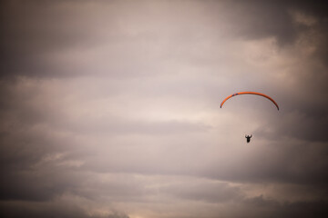 Paraglider flying alone, against a cloudy sky