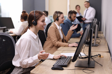 Call center operators working in modern office, focus on young woman with headset