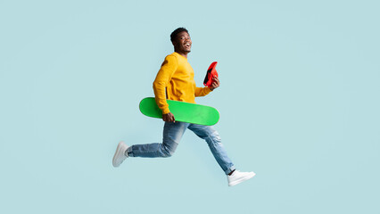 Emotional black guy running with skateboard towards copy space