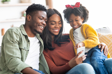 Technologies For Leisure. Black Family Of Three Using Smartphone At Home Together