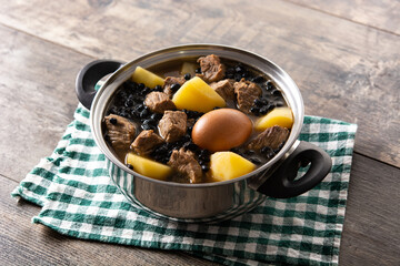 Traditional Jewish cholent in casserole on wooden table