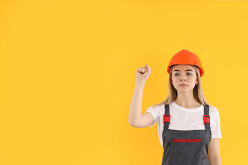 Girl power concept with female builder on yellow background