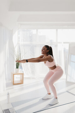 Young black woman working out in front of laptop computer at home, following online video tutorial indoors