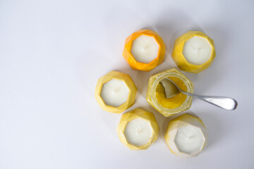 a spoon in a glass jar with honey is surrounded by handmade candles in plaster candlesticks with soy wax