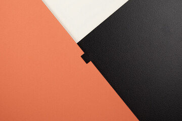 A fragment of an orange notebook and a white card, lying on a black satin background.