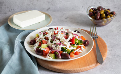 Bulgarian shopska salad with vegetables and cheese on wooden board with fork