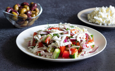 Bulgarian shopska salad with vegetables and brynza on dark concrete background