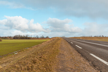 Empty road asphalt landscape among green spring meadows , blue sky,white clouds.