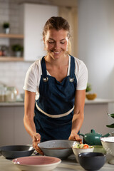 Young woman setting a table for lunch. Smiling happy woman preparing a delicious food.