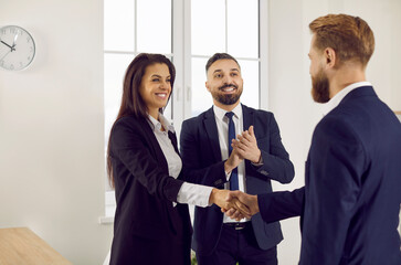 Happy people meeting in the office, making a profitable deal and exchanging handshakes. Team of smiling successful business partners confirming collaboration and shaking hands