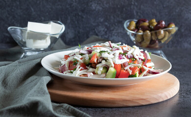 Shopska salad on wooden board, dark background background with gray textiles